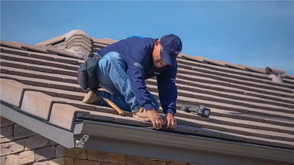 Technician installing gutter guards and cleaning roof gutters on a residential home in Southern California