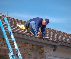 Technician performing gutter cleaning and maintenance on a residential roof in Southern California