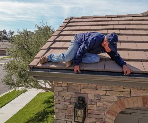 Technician inspecting and cleaning roof edge gutters as part of gutter guard and gutter cleaning services in Southern California