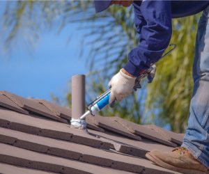 Roof technician sealing and securing roof tiles during professional repair service